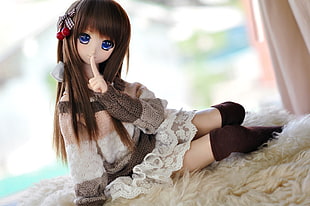 brown haired girl in white dress doll lying on beige surface