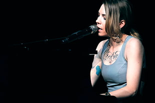 photo of a woman in gray sleeveless top using black microphone