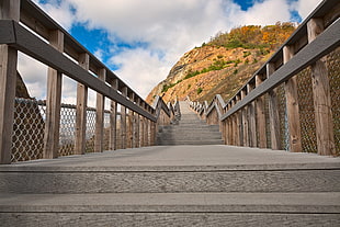brown wooden bridge through mountain during daytime, sideling hill