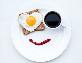 sunny side-up egg with wheat bread and a cup of coffee on white plate