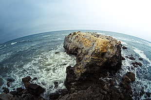 fish-eye photo of rock and body of water