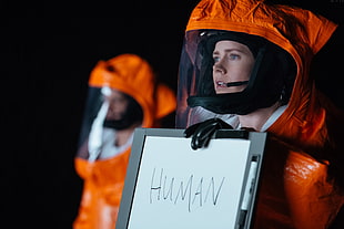 person wearing astronaut suit holding white magnetic board with human text