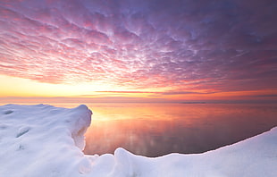 panoramic photograph of snow glacier facing ocean during golden hour