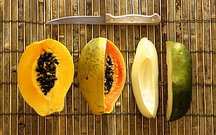 two sliced green and yellow papayas with knife