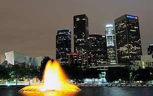 timelapse photo of a fountain near skyscrapers during nighttime