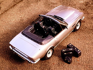 silver convertible coupe on brown concrete floor