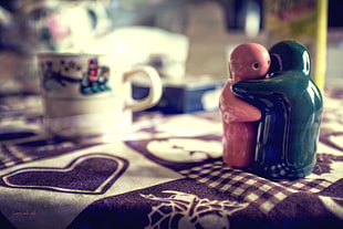 two red and green ceramic figurines, tablecloth, salt, Pepper, depth of field