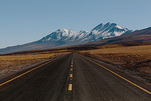 asphalt road leading to snow-capped mountain at daytime