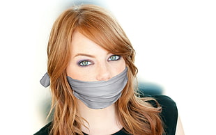 woman in black shirt with mouth covered by a grey cloth