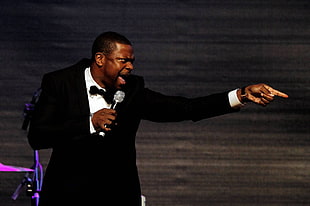 man in black suit jacket using microphone
