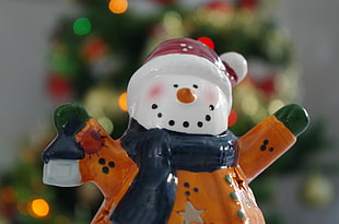 closeup photo of snowman in brown and blue scarf ceramic figurine