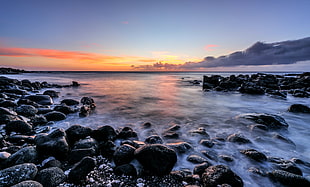 waves bashing rocks on the shore at sunset