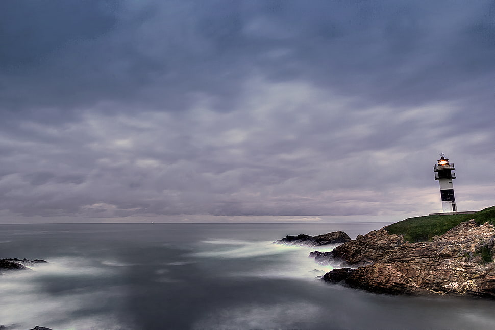 lighthouse under nimbus clouds during daytime HD wallpaper