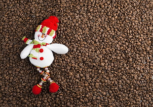 snowman with red and green beanie and scarf on bunch of brown coffee beans