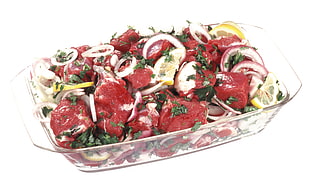 raw meats with onion rings in glass casserole