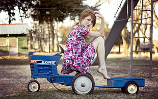 woman wearing pink and white dress sitting on blue Ford power tool