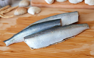 three cleaned fishes on brown wooden chopping board
