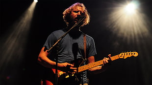 man in blue t-shirt playing guitar