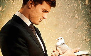 man in black and white formal suit holding a white pigeon