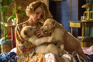 brown haired woman holding a two brown lion cubs