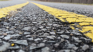closeup photo of black top road with yellow paint lines