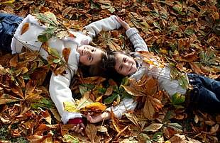 two children wearing white shirts lying on ground