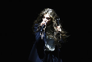 woman holds microphone and stand while singing