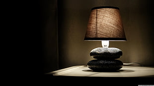 black stone table lamp with brown lamp shade on white table turned on