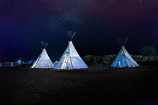 three white teepee tents during nighttime