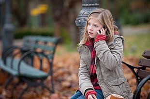 girl holding phone calling someone standing beside black post