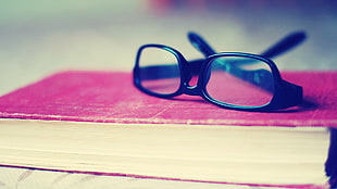 black framed eyeglasses on red book