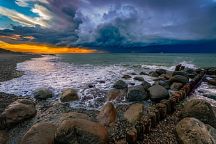 photography of rocky sea bay during cloudy day