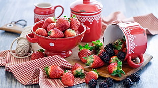 pile of strawberries on red canister and bowls