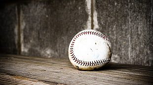 closeup photography of white baseball on brown wooden surface
