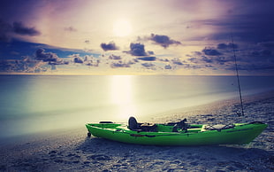green kayak on beach during sunset