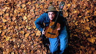 man holding brown classical guitar