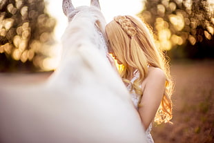 selective photo of woman wearing white dress holding white horse
