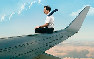 man sits on airplane wing during daytime