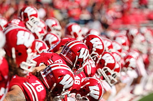 Football players in red and white W helmets standing side by side during daytime HD wallpaper