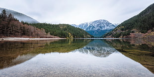 landscape photography of three mountain range in front of body of water during daytime