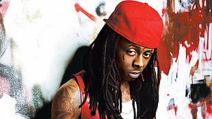 Lil' Wayne in white top and red cap against white wall