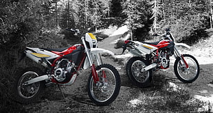 two black, red, and white motocross dirt bikes parked on rough road
