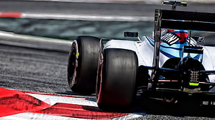 white and blue formula 1 on grey path