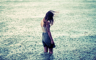 woman in dress stood under the heavy rain at the sea