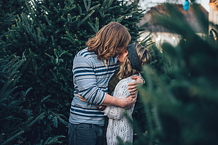 man kissing woman while surrounded by trees during daytime HD wallpaper