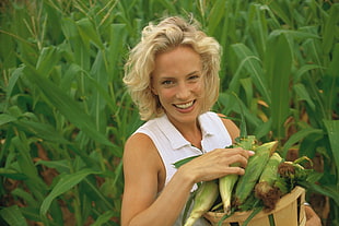 woman in white collared sleeveless shirt near green corn field