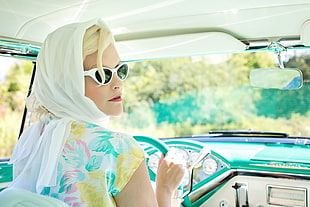 woman wearing white scarf and white and multi-colored flower printed top while holding steering wheel