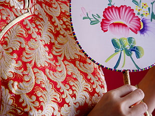 person holding white and multicolored floral hand fan