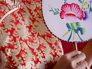 person holding white and multicolored floral hand fan