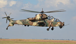 brown, black, and brown camouflage helicopter flying during daytime